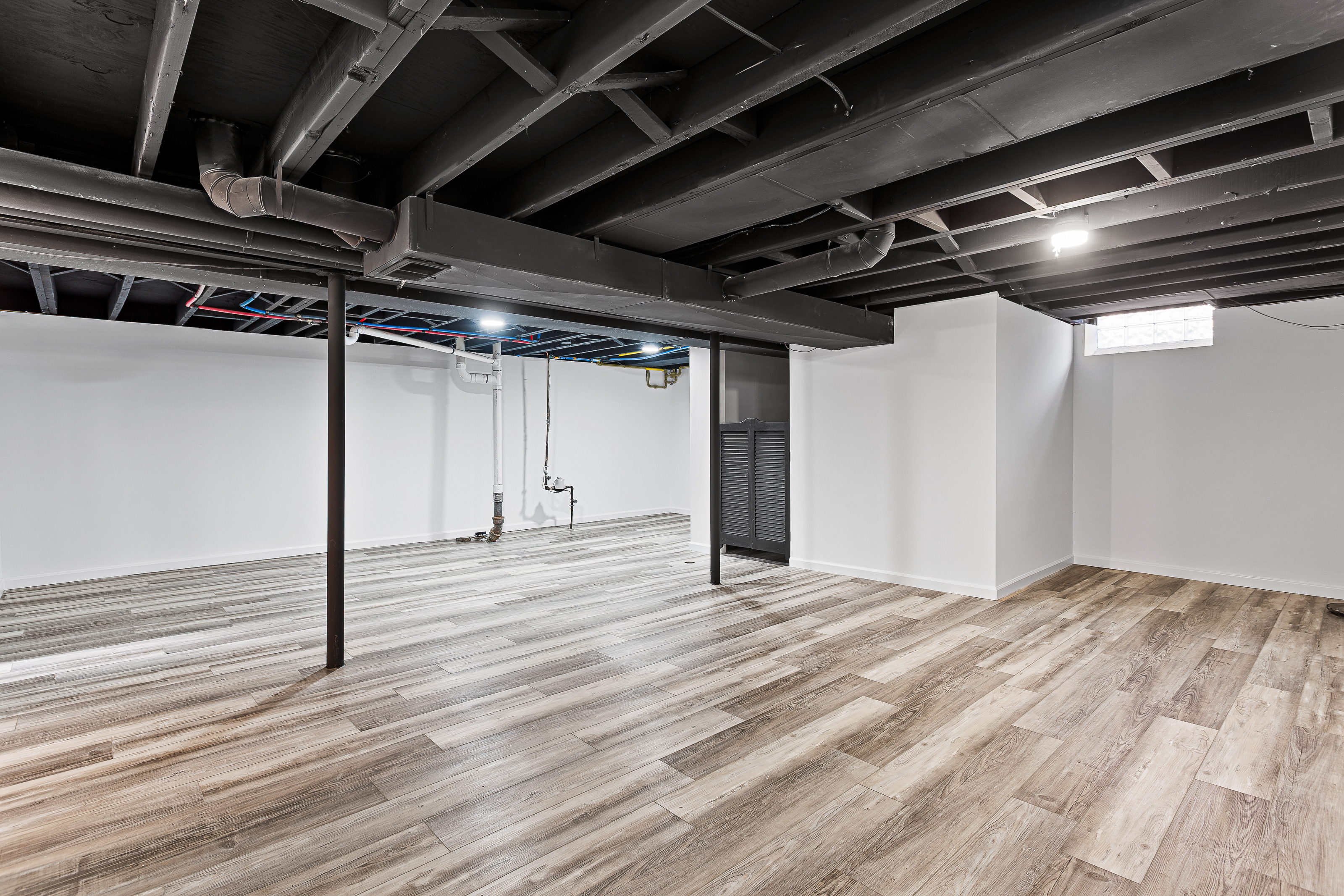 Finished basement with new flooring, painted walls, and open layout