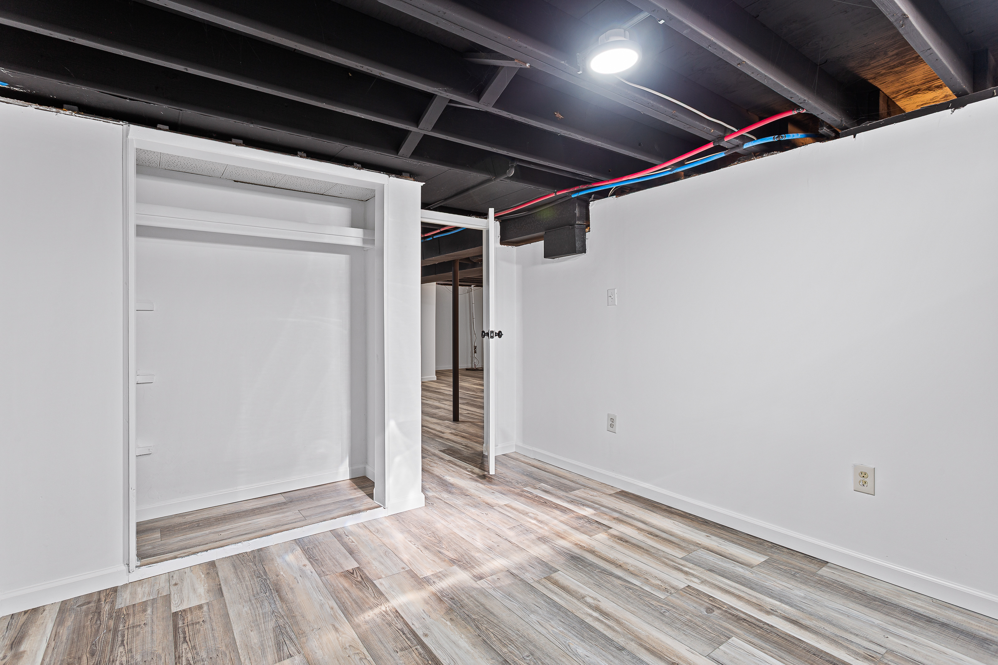 Finished basement room with closet and hallway leading to main open area