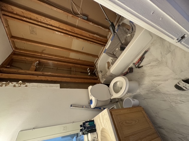 Bathroom mid-renovation with tub surround stripped to studs