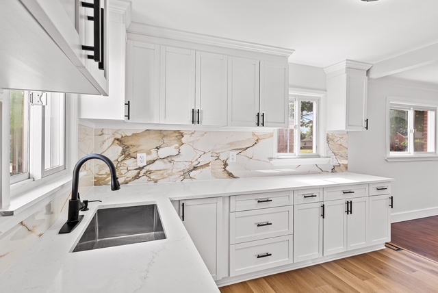Finished kitchen sink area with white cabinets, marble countertop, and matte black faucet