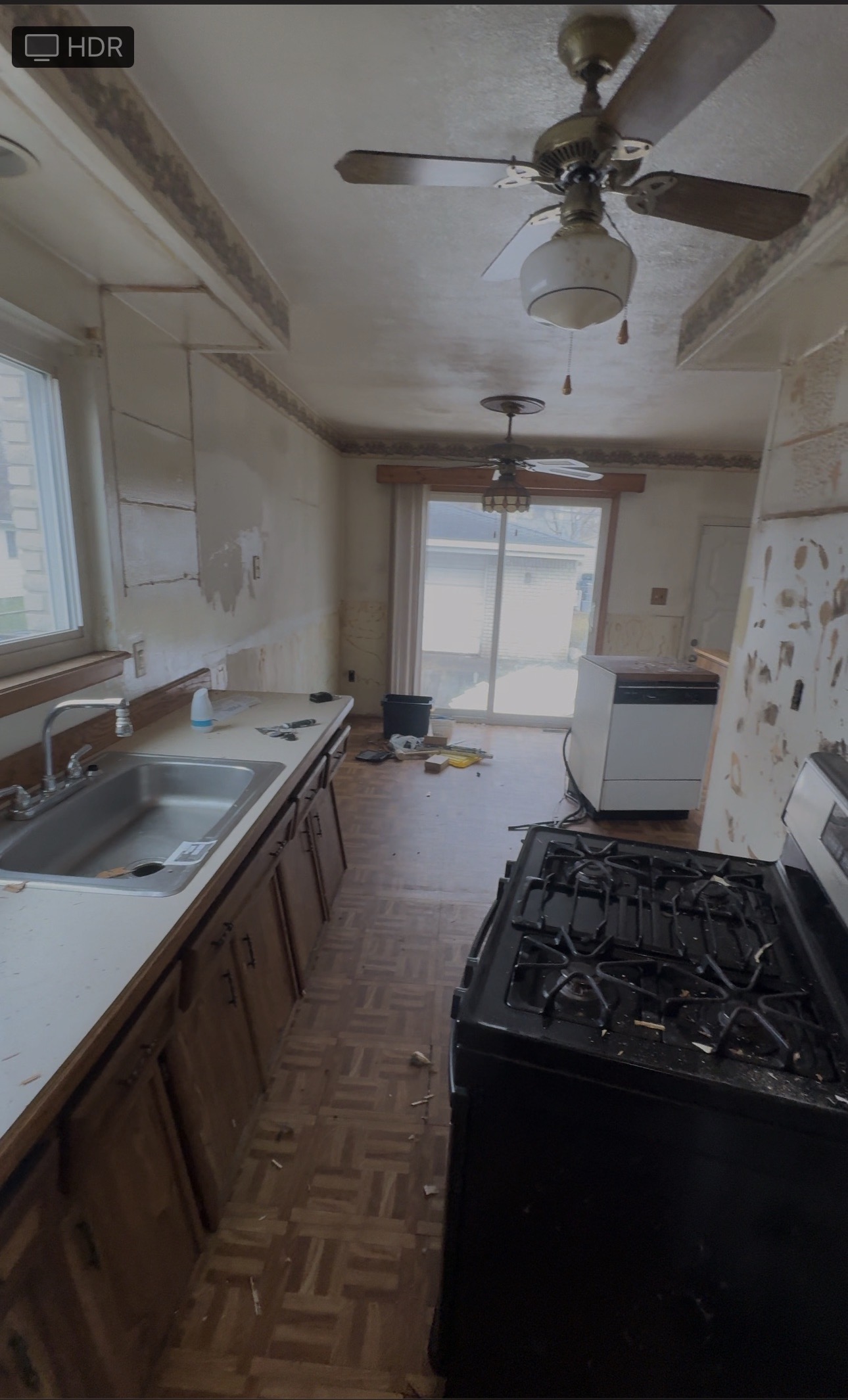 Outdated galley kitchen with worn cabinets and parquet flooring